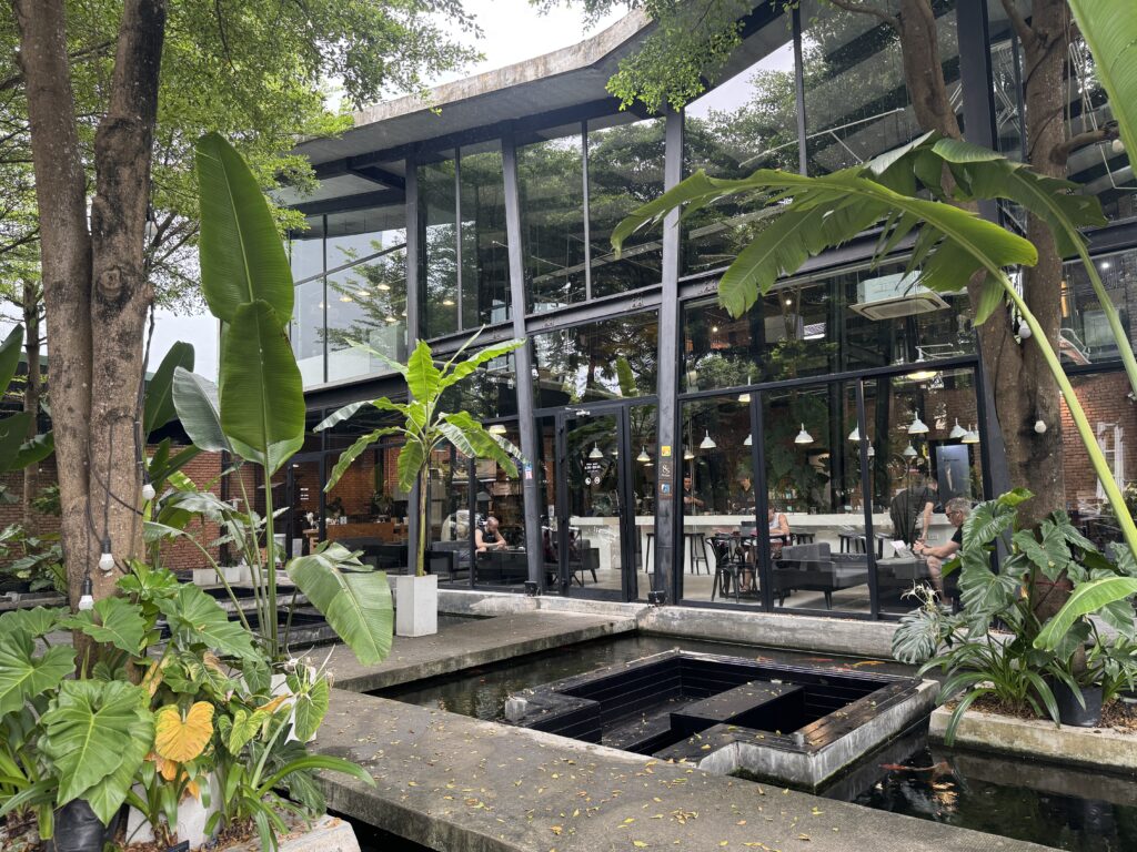Glass-walled exterior of 43 Factory Coffee Roaster, surrounded by greenery