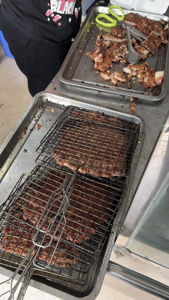Grilled minced pork spread across a charcoal grill for bun cha in Hanoi