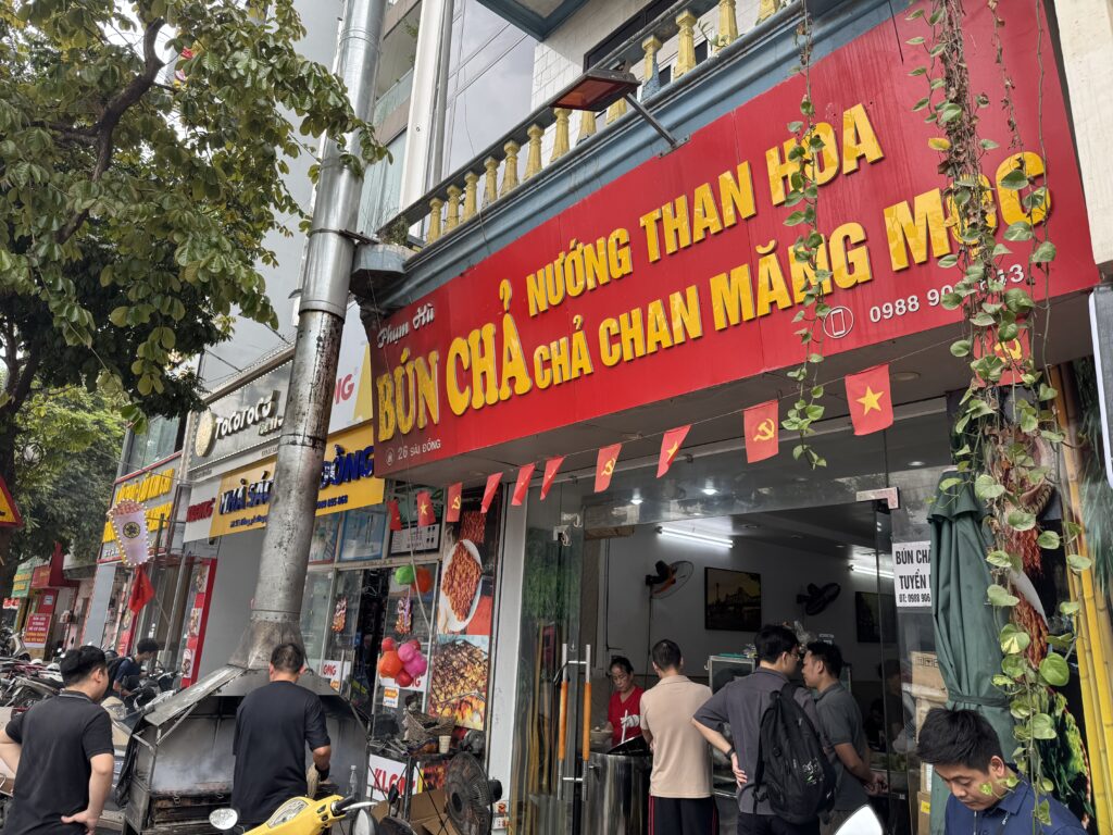 Busy local bun cha restaurant in Hanoi with motorbikes and crowded seating