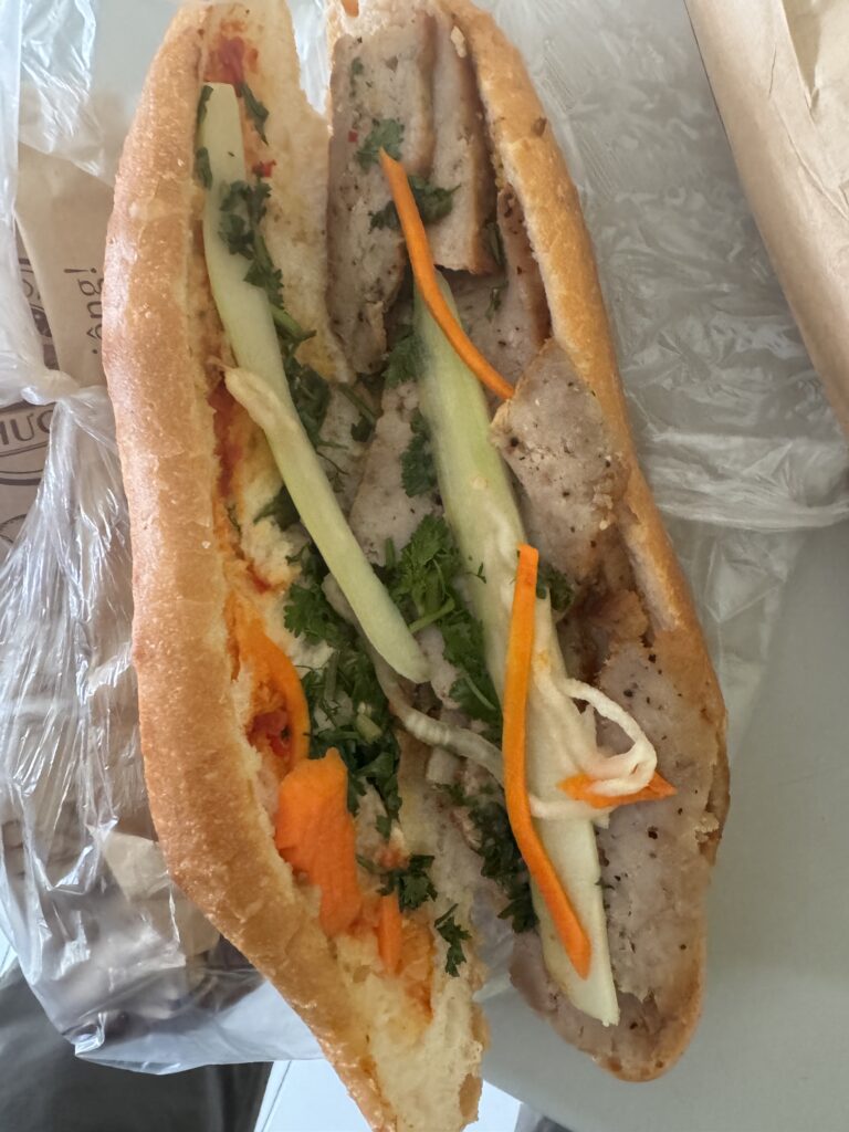 Vietnamese banh mi sandwich with sliced meat, pickled vegetables, cucumber, and herbs