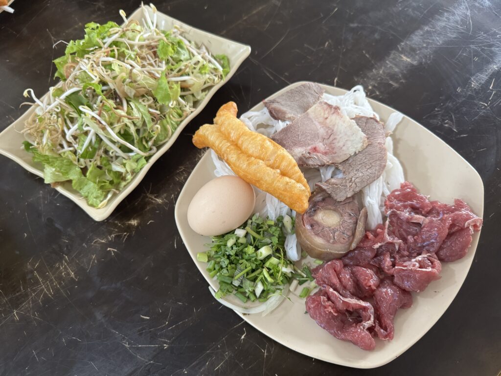 Ingredients for hot stone bowl water buffalo pho including meat, noodles and egg in Hung Yen, Vietnam.