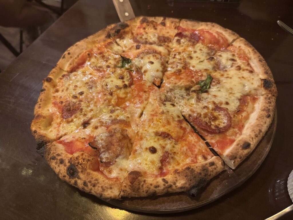 Wood-fired pizza with tomato, cheese, and salami at Domenica Napoli Pizza in Hanoi